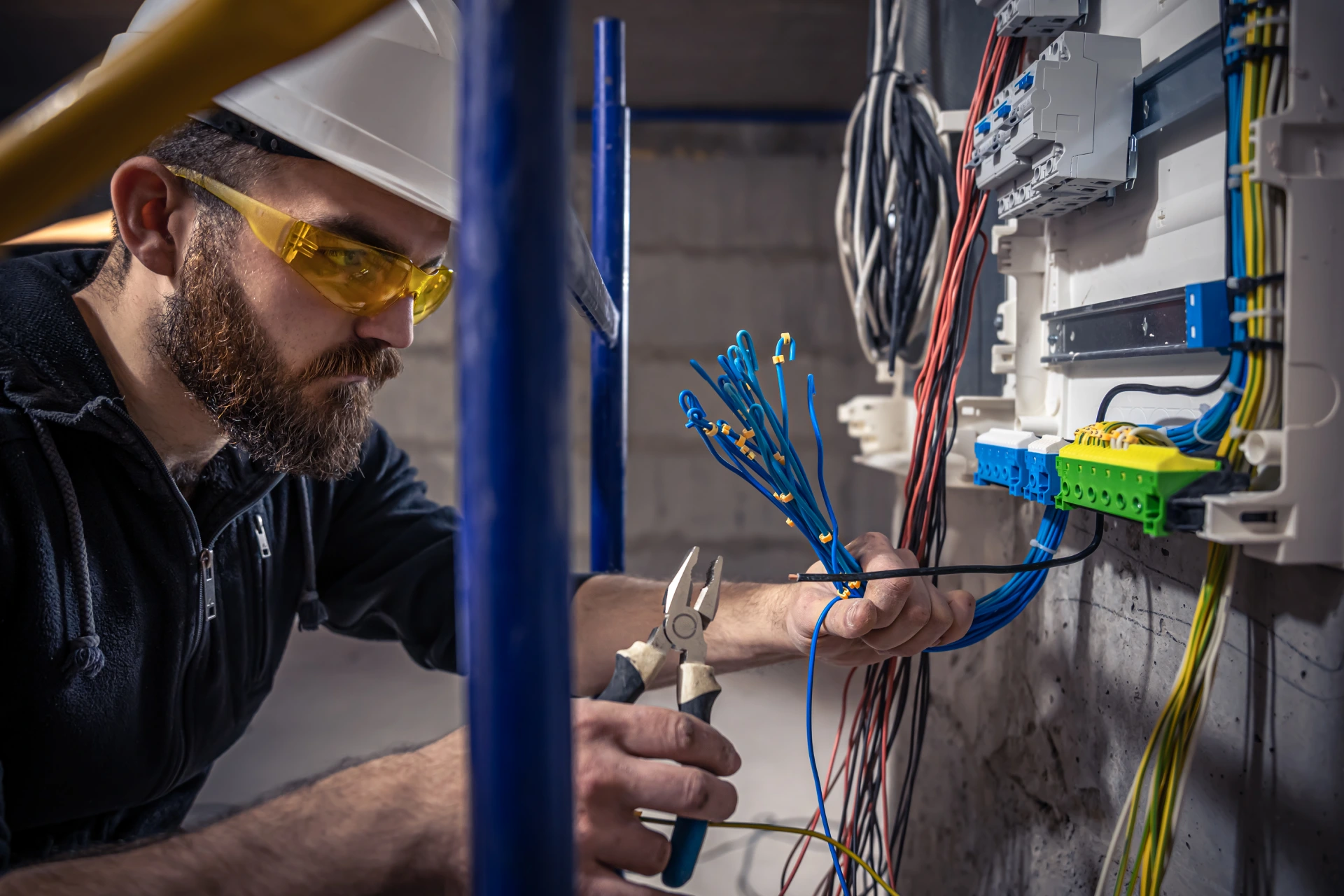 male electrician works switchboard with electrical connecting cable