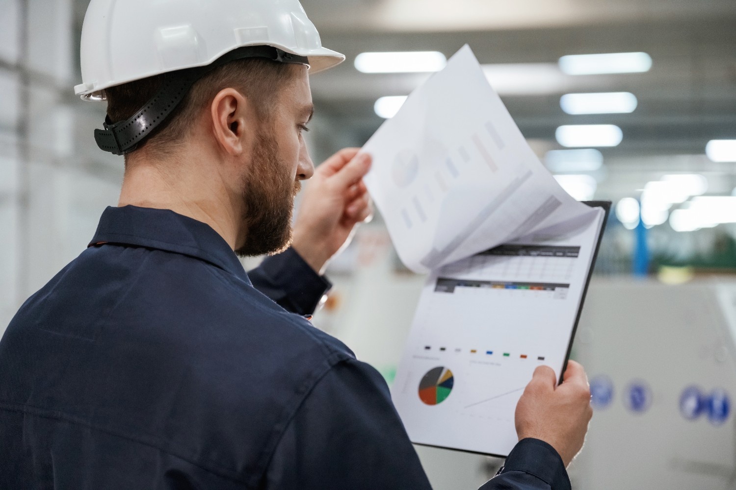 turning pages documents factory worker is indoors with hard hat