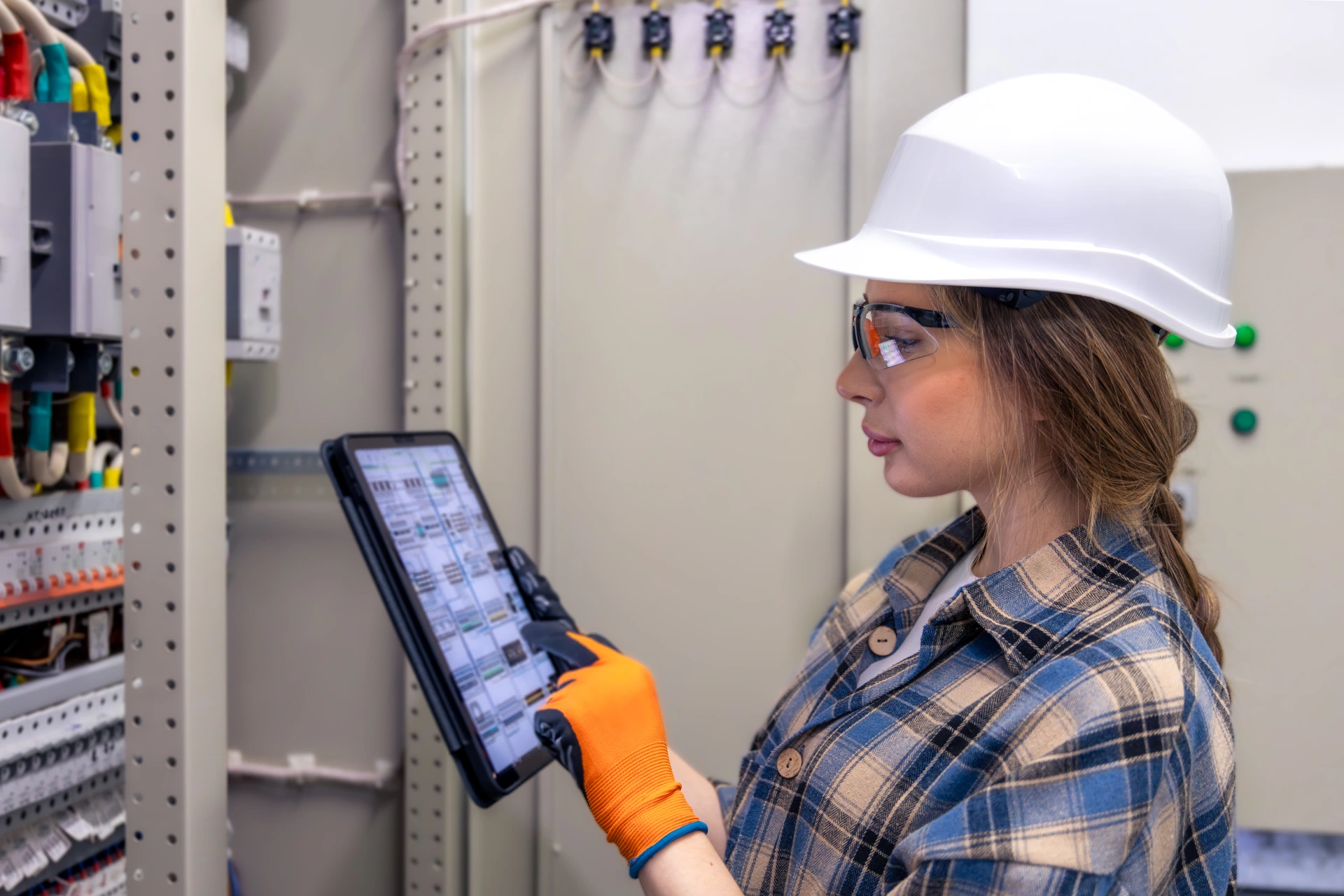 woman engineer follows tablet checklist by electrical panel digital protocol