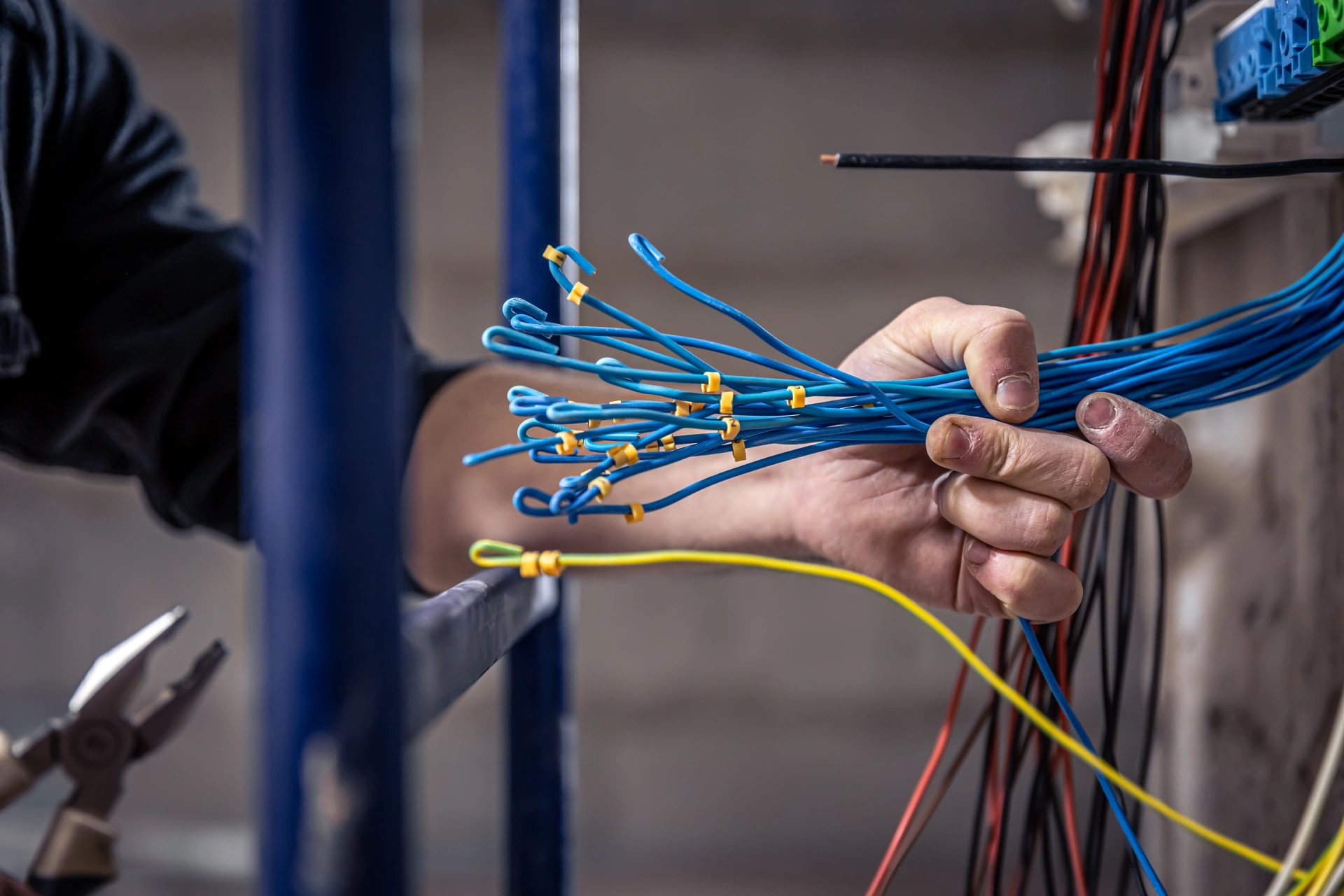 male electrician works switchboard with electrical connecting cable